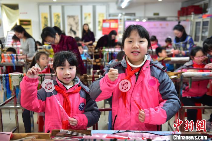 圖為小學(xué)生展示繡制好的2022年北京冬奧會吉祥物“冰墩墩”形象?！∮髟屏?攝