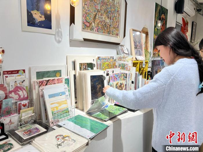 圖為藝術(shù)品商店內(nèi)，顧客挑選插畫作品?！＄婌?攝