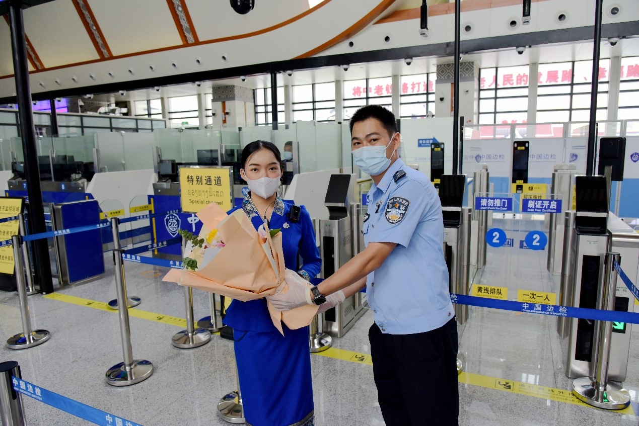 磨憨出入境邊防檢查站民警為中老鐵路第100萬(wàn)名出入境旅客，D888次國(guó)際旅客列車?yán)蠐爰藙?wù)員森達(dá)拉·妮緹婭（Sengdala Nitiya），送上鮮花。黃遠(yuǎn)飛 攝