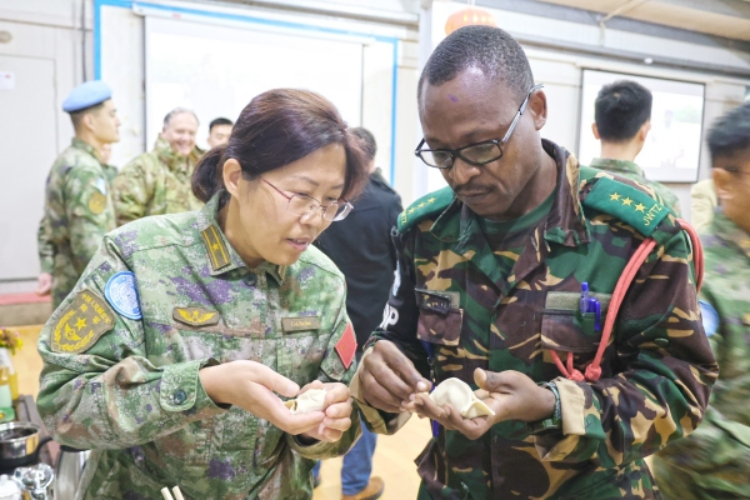 圖為維和官兵與外軍人員共同包餃子。胡光明攝