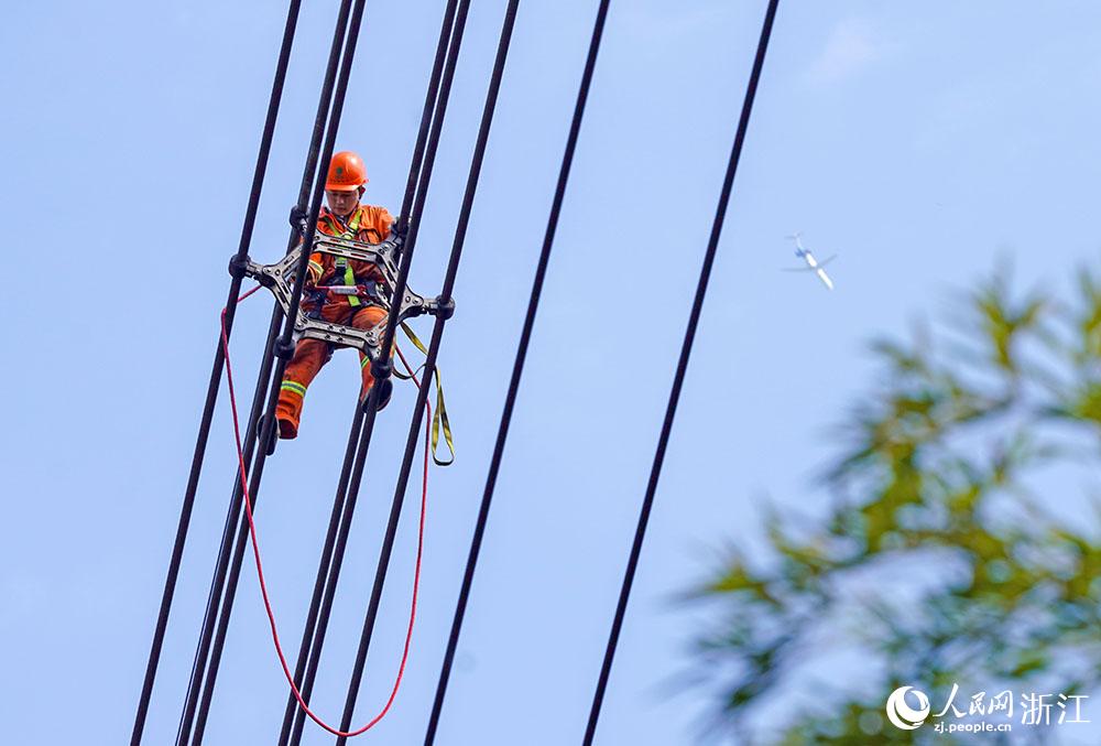 3月11日，在浙江省諸暨市河上鎮(zhèn)，浙江省送變電工程有限公司檢修人員在高空的導(dǎo)線上進(jìn)行線路檢修維護(hù)。人民網(wǎng) 章勇濤攝