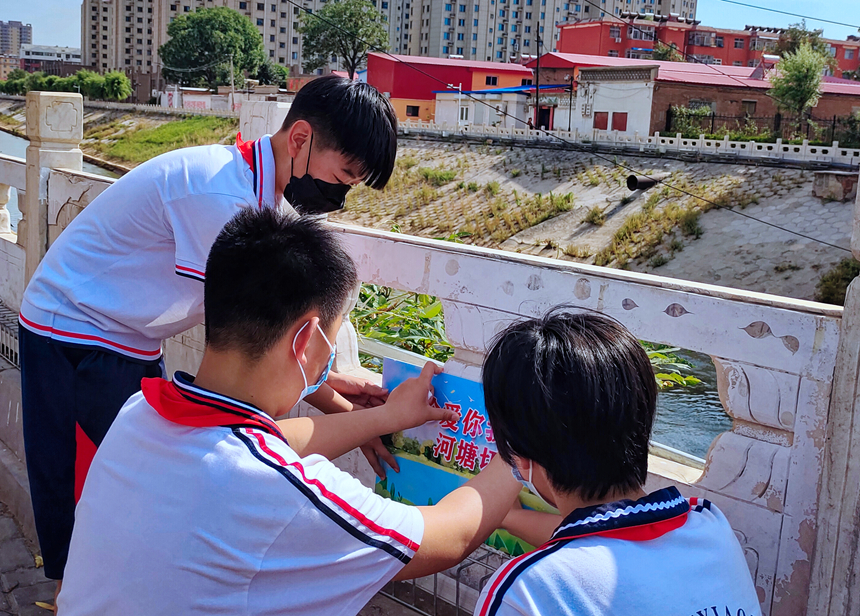 徐水小學(xué)學(xué)雷鋒志愿者在瀑河河邊張貼防溺水警示標(biāo)語。 徐水區(qū)委宣傳部供圖