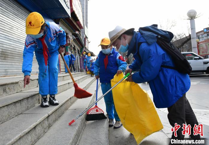 圖為拉薩市小學(xué)生打掃街道?！∝暩聛?lái)松 攝