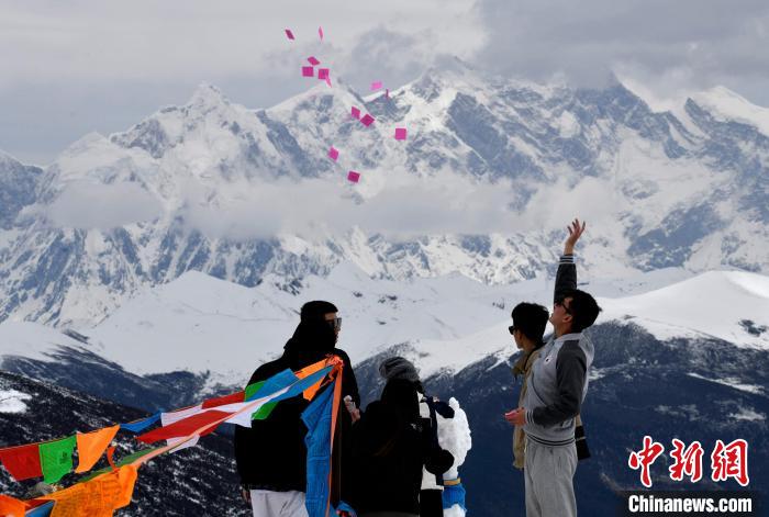 圖為5月14日，游客在西藏林芝色季拉山觀景臺(tái)拋灑“隆達(dá)”(風(fēng)馬旗，藏族民眾的一種祈福方式)?！±盍?攝