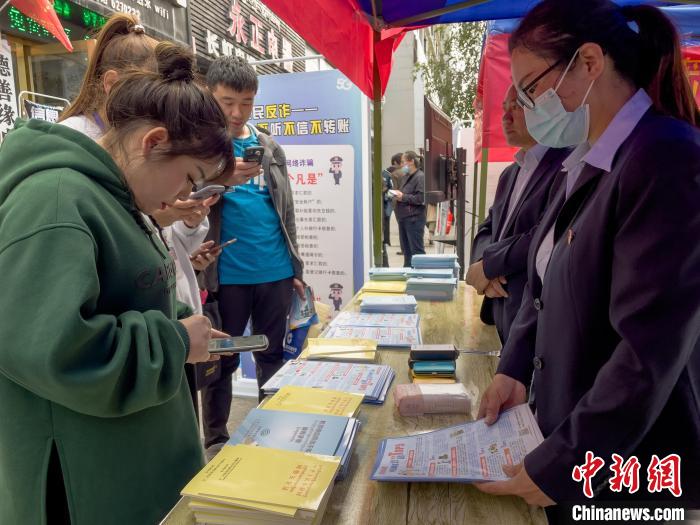 圖為工作人員正在向路過(guò)市民介紹國(guó)家反詐中心軟件的功能?！≈x牧 攝